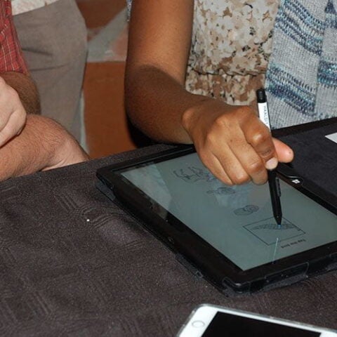 One person training another person on how to use a tablet to do an assessment
