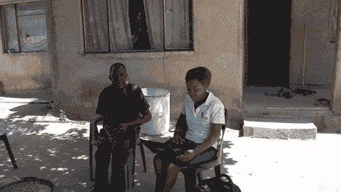 An older South African man and a healthcare worker do an intake sitting outside in rural South Africa
