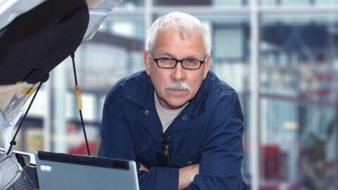 Older man using a computer to service a car