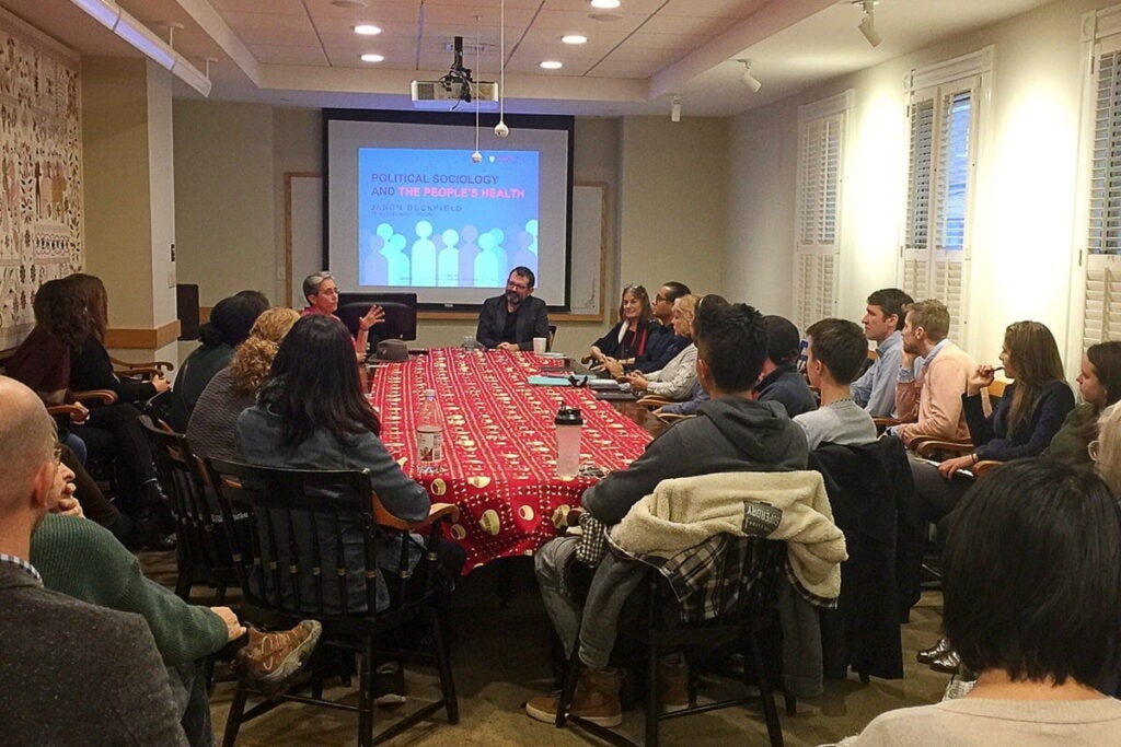 People sit at conference table to hear Jason's presentation about his book