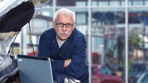 Older man working as a mechanic using a laptop