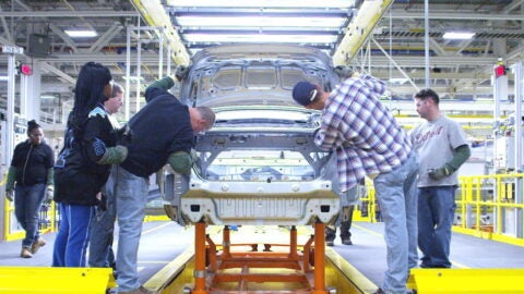 Assembly workers work on a Chrysler car at a Michigan plant.