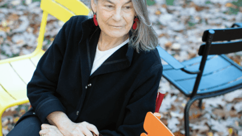 Lisa Berkman sitting in Harvard Yard with colorful chairs