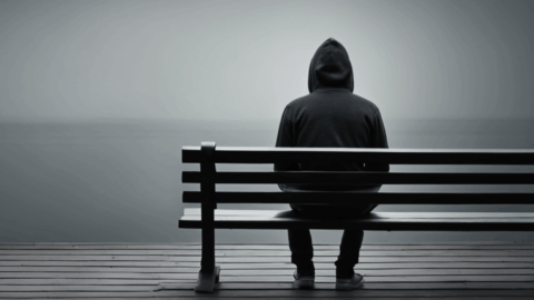 Lonely looking man sits near a lake