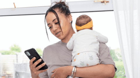 New mother with infant looking at a text message reminder