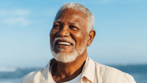 Black man at the ocean looking optimistic