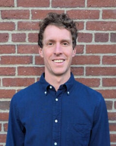 Tom Lindman standing in front of Harvard brick wall